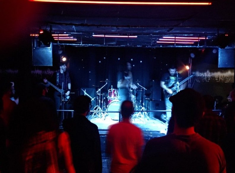 Banda no palco sob luz vermelha e azul